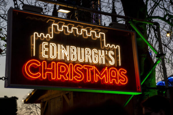 Showing a neon sign advertising Edinburgh's Christmas Market.
