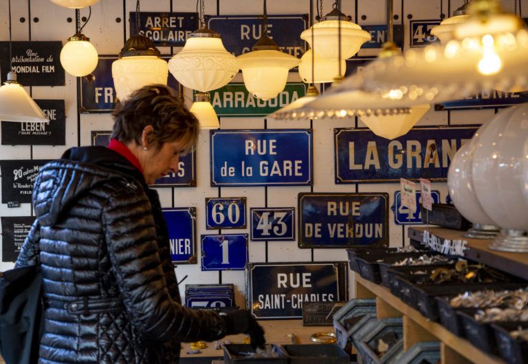 Showing a woman shopping at a store full of Parisian roadsigns.